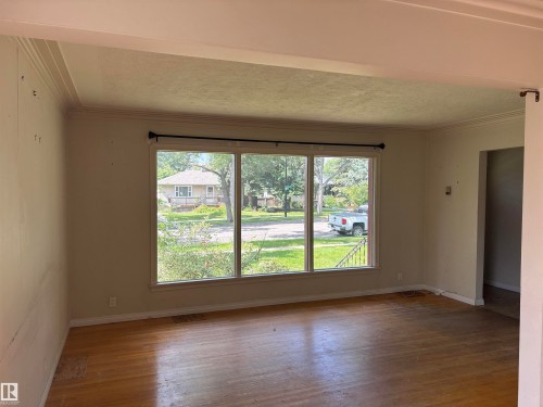 Bright living space featuring expansive triple-panel sliding glass doors with black framing, hardwood flooring throughout, and abundant natural light - 10845 140 Street Nw, Edmonton, AB - Indoor Photo Showing Other Room