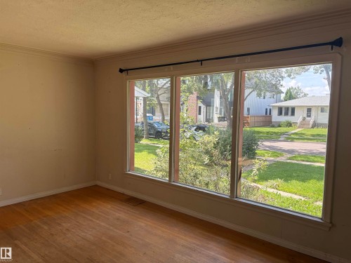 Bright, light-filled room with expansive triple-pane sliding glass doors overlooking manicured lawn and mature landscaping - 10845 140 Street Nw, Edmonton, AB - Indoor Photo Showing Other Room