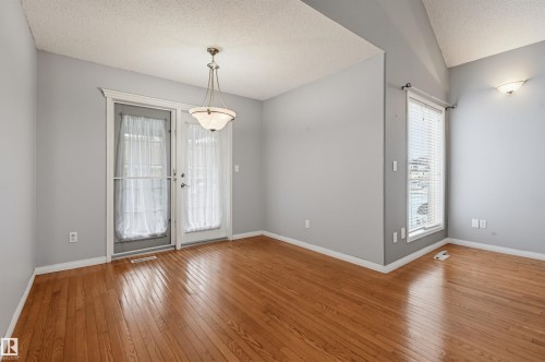 Hardwood flooring, painted walls, pendant light fixture, wall-mounted light fixture, and a window with blinds - #8 1920 Millwoods Rd E Nw, Edmonton, AB - Indoor Photo Showing Other Room
