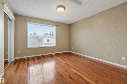 Hardwood flooring, painted walls, ceiling light fixture, and a built-in closet with mirrored sliding doors - #8 1920 Millwoods Rd E Nw, Edmonton, AB - Indoor Photo Showing Other Room