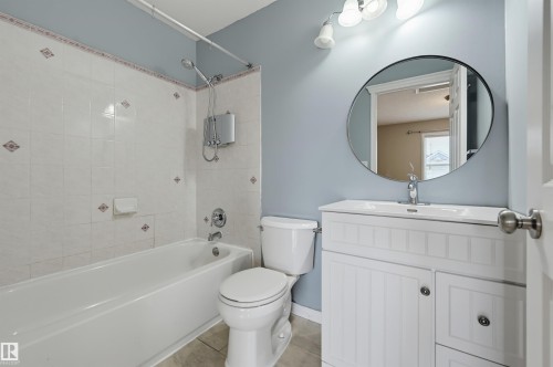 White tile tub surround with decorative accents, an overhead shower fixture, and a single-lever faucet - #8 1920 Millwoods Rd E Nw, Edmonton, AB - Indoor Photo Showing Bathroom