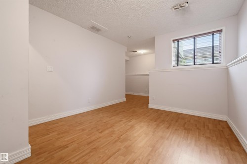 Wood-finish flooring, white painted walls, window with horizontal blinds, and overhead lighting - #8 1920 Millwoods Rd E Nw, Edmonton, AB - Indoor Photo Showing Other Room