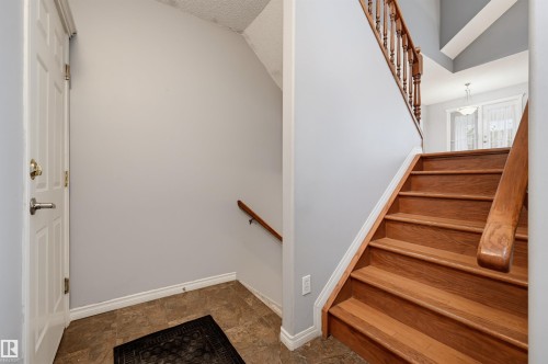 Wood staircase with baluster railing, tile flooring, and white trim - #8 1920 Millwoods Rd E Nw, Edmonton, AB - Indoor Photo Showing Other Room