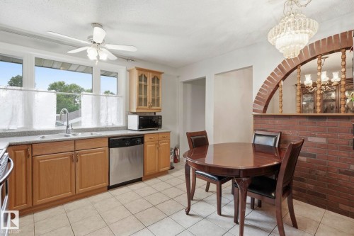 Kitchen featuring wood-finish cabinetry, stainless steel dishwasher, tile flooring, and a ceiling fan - 7 Graham Avenue, St. Albert, AB - Indoor