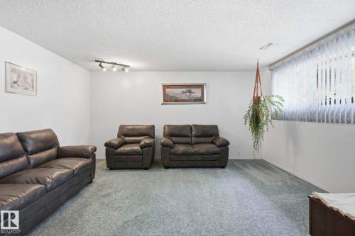 Recessed window with vertical blinds, textured white ceiling, track lighting fixture, and light-colored carpeting - 7 Graham Avenue, St. Albert, AB - Indoor Photo Showing Living Room