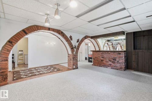 Brick archways, recessed lighting, drop ceiling, wood-finish paneling, and a built-in brick bar - 7 Graham Avenue, St. Albert, AB - Indoor Photo Showing Other Room