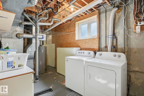 Utility space with exposed ceiling joists, concrete walls, a window, and a water heater - 7 Graham Avenue, St. Albert, AB - Indoor Photo Showing Laundry Room