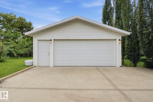 Attached two-car garage with white paneled doors, white vinyl siding, and exterior lighting fixtures - 7 Graham Avenue, St. Albert, AB - Outdoor With Exterior