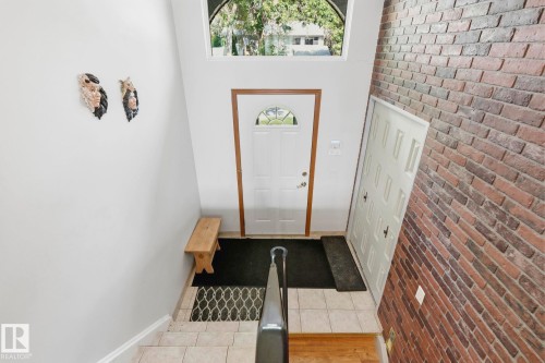 Entryway featuring a white paneled door, high-set arch window, brick accent wall, and tiled flooring - 7 Graham Avenue, St. Albert, AB - Indoor Photo Showing Other Room