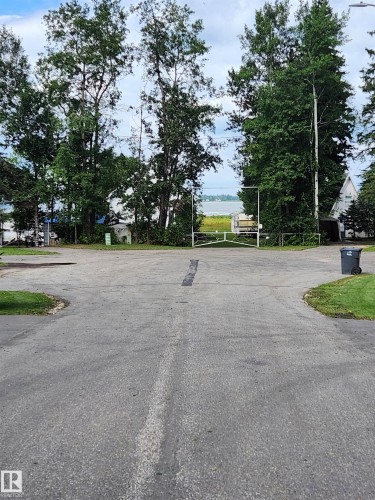 Paved driveway with lush perimeter landscaping and a distant water feature - #413 55230 Rge Road 10, Rural Sturgeon County, AB 