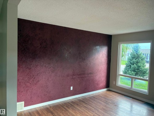 Wood-finish flooring, textured accent wall, white trim, and a large window - 13831 23 Street Nw, Edmonton, AB - Indoor Photo Showing Other Room