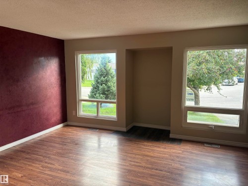 Wood-finish flooring, accent wall, built-in wall niche, and multiple windows - 13831 23 Street Nw, Edmonton, AB - Indoor Photo Showing Other Room