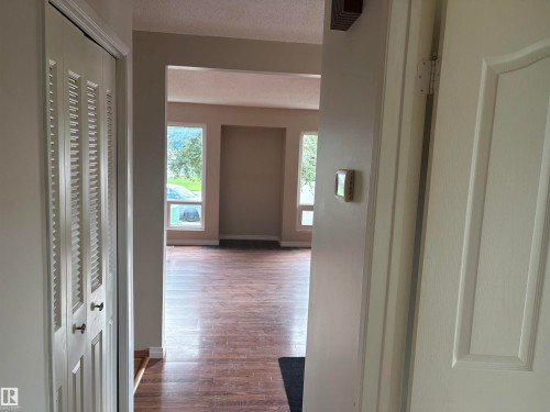 Arched entryway leading to a living area with wood-finish flooring and multiple windows - 13831 23 Street Nw, Edmonton, AB - Indoor Photo Showing Other Room