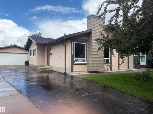 Stucco exterior with contrasting trim, attached garage with white door, and a prominent chimney feature - 13831 23 Street Nw, Edmonton, AB - Outdoor