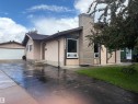 Stucco exterior with contrasting trim, attached garage with white door, and a prominent chimney feature - 13831 23 Street Nw, Edmonton, AB  - Outdoor 