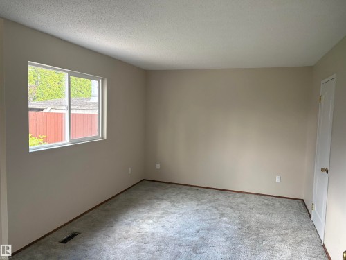 Neutral wall color, window with white trim, textured ceiling, and a white interior door - 13831 23 Street Nw, Edmonton, AB - Indoor Photo Showing Other Room