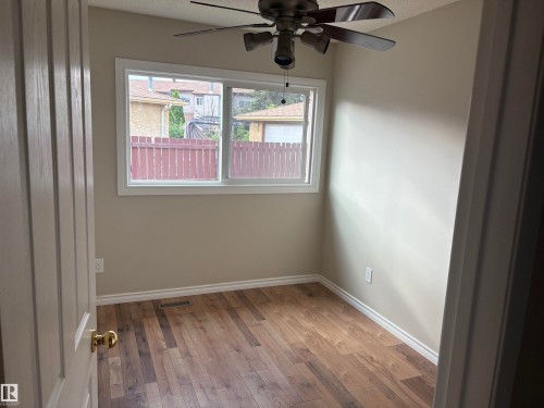 Wood-finish flooring, neutral wall tones, white trim, and a ceiling fan with integrated lighting - 13831 23 Street Nw, Edmonton, AB - Indoor Photo Showing Other Room