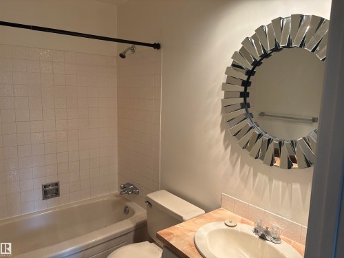 Bathtub with tiled surround, shower fixture, and a decorative mirror - 13831 23 Street Nw, Edmonton, AB - Indoor Photo Showing Bathroom