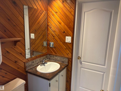 Wood-paneled walls, vanity with integrated sink, mosaic tile backsplash, and wall-mounted mirror - 13831 23 Street Nw, Edmonton, AB - Indoor Photo Showing Bathroom