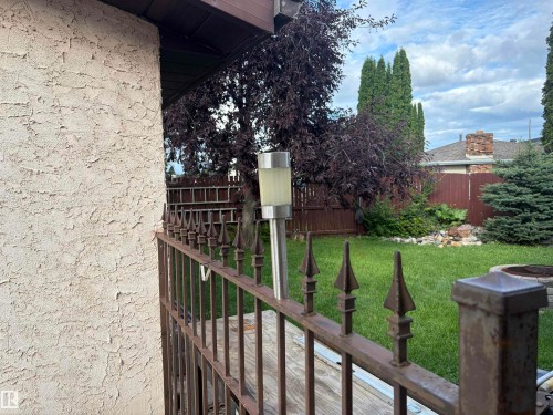 Stucco exterior finish, wrought iron fencing, manicured lawn, and mature landscaping - 13831 23 Street Nw, Edmonton, AB - Outdoor