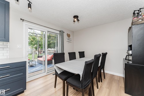 Sliding glass door, wood-finish flooring, white walls, dark cabinetry, track lighting - 4521 29 Avenue Nw, Edmonton, AB - Indoor Photo Showing Dining Room
