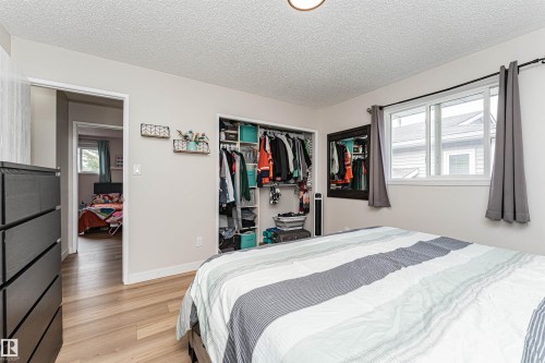 Wood-finish flooring, recessed closet with built-in shelving, white trim, and a window with a white frame - 4521 29 Avenue Nw, Edmonton, AB - Indoor Photo Showing Bedroom