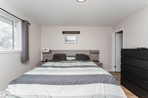 Wall-mounted light fixture, light gray wall finishes, wood-finish flooring, and white trim - 4521 29 Avenue Nw, Edmonton, AB - Indoor Photo Showing Bedroom