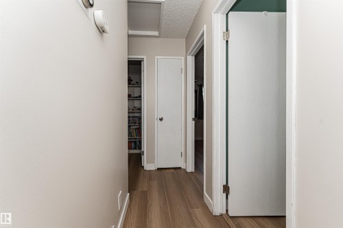 Hallway with wood-finish flooring, white painted walls, and multiple doorways - 4521 29 Avenue Nw, Edmonton, AB - Indoor Photo Showing Other Room