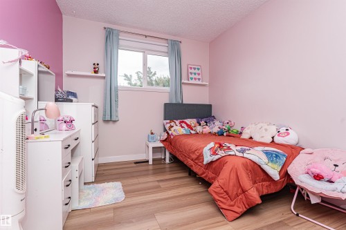 Wood-finish flooring with a textured ceiling, featuring a window with privacy blinds and a floating wall shelf - 4521 29 Avenue Nw, Edmonton, AB - Indoor Photo Showing Bedroom