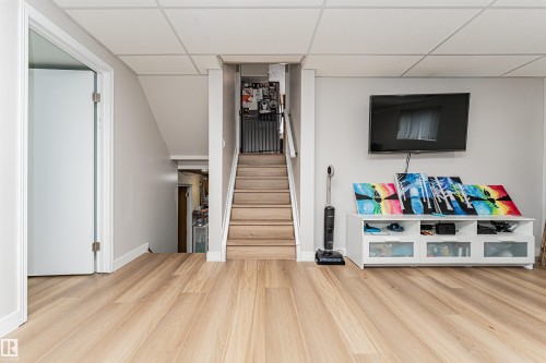 Light wood-finish flooring extending from the main area to the staircase - 4521 29 Avenue Nw, Edmonton, AB - Indoor Photo Showing Other Room
