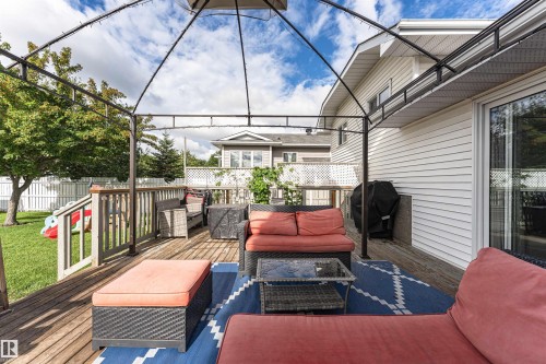Expansive outdoor deck with a metal gazebo frame, white siding, and sliding glass doors - 4521 29 Avenue Nw, Edmonton, AB - Outdoor With Deck Patio Veranda With Exterior