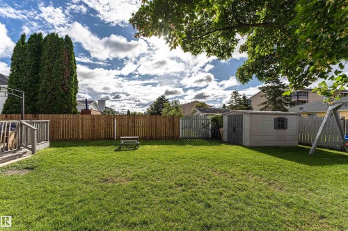 Expansive green lawn with a wood privacy fence, featuring a raised wood deck, a storage shed, and mature trees - 4521 29 Avenue Nw, Edmonton, AB - Outdoor