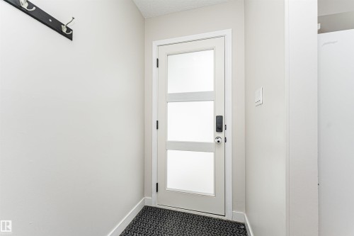 Entry door with frosted glass panels, black hardware, and a black coat rack - 4521 29 Avenue Nw, Edmonton, AB - Indoor Photo Showing Other Room