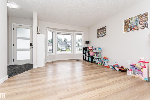 Light wood-finish flooring, bay window with multiple panes, contemporary entry door with frosted panels, and recessed ceiling lighting - 4521 29 Avenue Nw, Edmonton, AB - Indoor Photo Showing Other Room