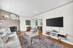 Brick fireplace with a metal grate and sconce lighting, wood-finish flooring, and white walls - 