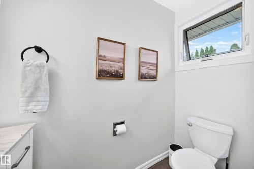 White-framed casement window, wall-mounted towel ring, built-in toilet paper holder, white toilet - 16406 87A Avenue Nw, Edmonton, AB - Indoor Photo Showing Bathroom