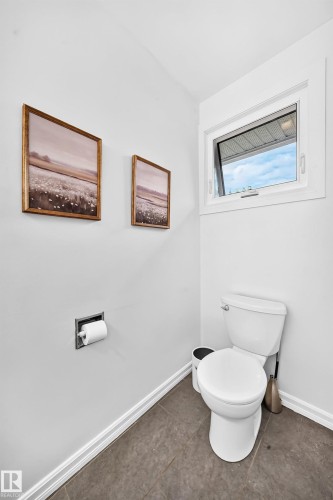 White toilet with a built-in toilet paper holder and a single casement window - 16406 87A Avenue Nw, Edmonton, AB - Indoor Photo Showing Bathroom