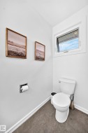 White toilet with a built-in toilet paper holder and a single casement window - 