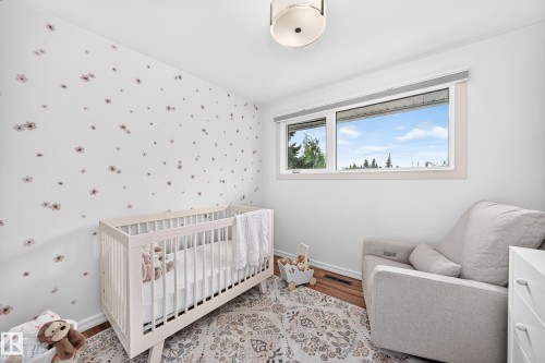 Bright room featuring a large window, a decorative wall, a flush-mount ceiling light, and wood-finish flooring - 16406 87A Avenue Nw, Edmonton, AB - Indoor Photo Showing Bedroom