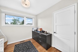Wood-finish flooring, white paneled door, flush-mount ceiling light, and a horizontal window with white trim - 
