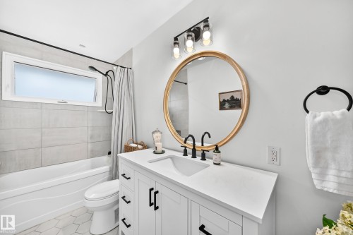 White vanity with integrated sink, black fixtures, and round gold-framed mirror - 16406 87A Avenue Nw, Edmonton, AB - Indoor Photo Showing Bathroom
