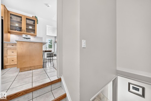 Kitchen featuring wood-finish cabinetry with glass inserts, light countertop, and tile backsplash - 16406 87A Avenue Nw, Edmonton, AB - Indoor