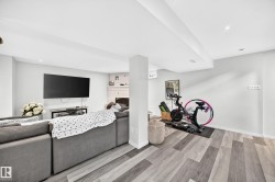 Recessed lighting, wood-finish flooring, white painted walls, and a white brick fireplace - 