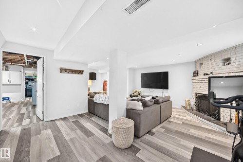 Recessed lighting, wood-finish flooring, and a white brick fireplace with a built-in hearth - 16406 87A Avenue Nw, Edmonton, AB - Indoor With Fireplace