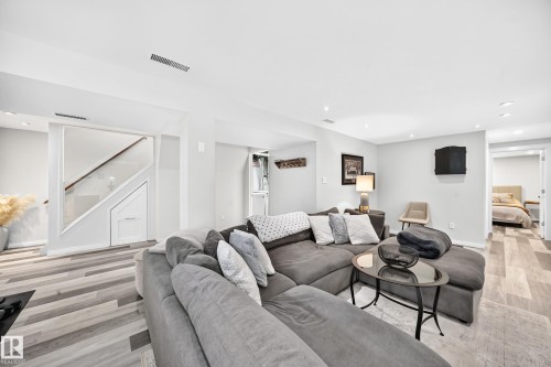 Spacious living area featuring recessed lighting, wood-finish flooring, a built-in staircase with storage, and an open doorway to an additional room - 16406 87A Avenue Nw, Edmonton, AB - Indoor Photo Showing Living Room