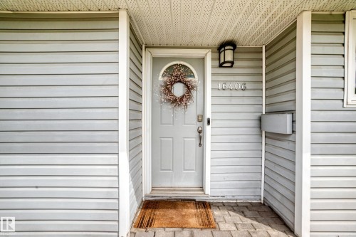 Entry door with an arched window accent, flanked by light-colored horizontal siding and a paver walkway - 16406 87A Avenue Nw, Edmonton, AB - Outdoor With Exterior