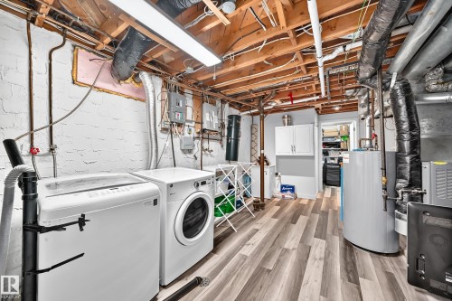 Laundry area featuring wood-finish flooring, white painted brick walls, exposed ceiling joists, and a water heater - 16406 87A Avenue Nw, Edmonton, AB - Indoor Photo Showing Laundry Room