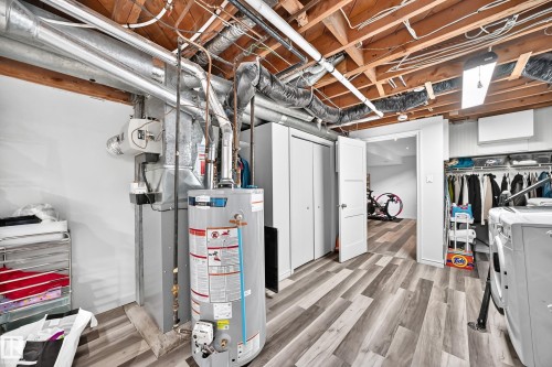 Wood-finish flooring, white bifold closet doors, and a built-in laundry area - 16406 87A Avenue Nw, Edmonton, AB - Indoor Photo Showing Basement