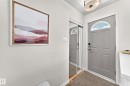 Entryway featuring a paneled door with an arched decorative glass insert, wood-finish flooring, and a mirrored closet door - 16406 87A Avenue Nw, Edmonton, AB  - Indoor Photo Showing Other Room 