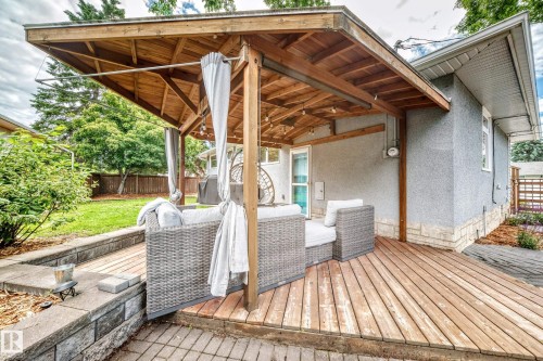 Covered wood deck featuring exposed beam ceiling, wood-plank flooring, and stucco exterior - 16406 87A Avenue Nw, Edmonton, AB - Outdoor With Deck Patio Veranda With Exterior